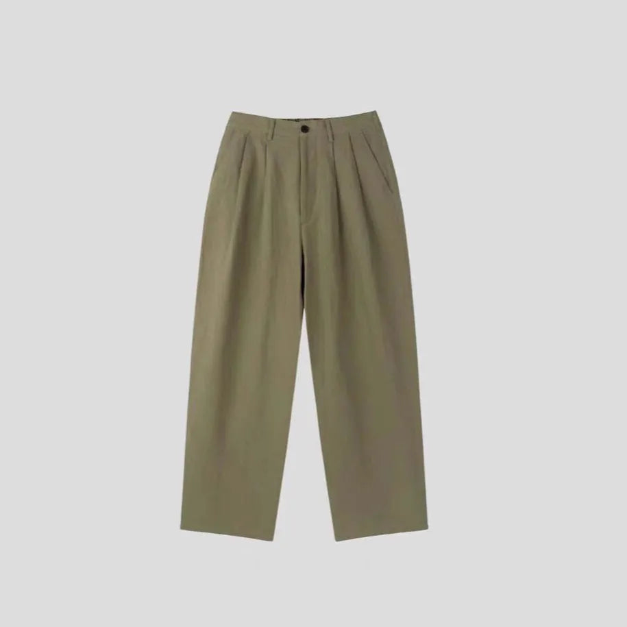 Men's apricot coloured wide-leg cotton linen trousers with a mid waist and zip fly on a neutral background.