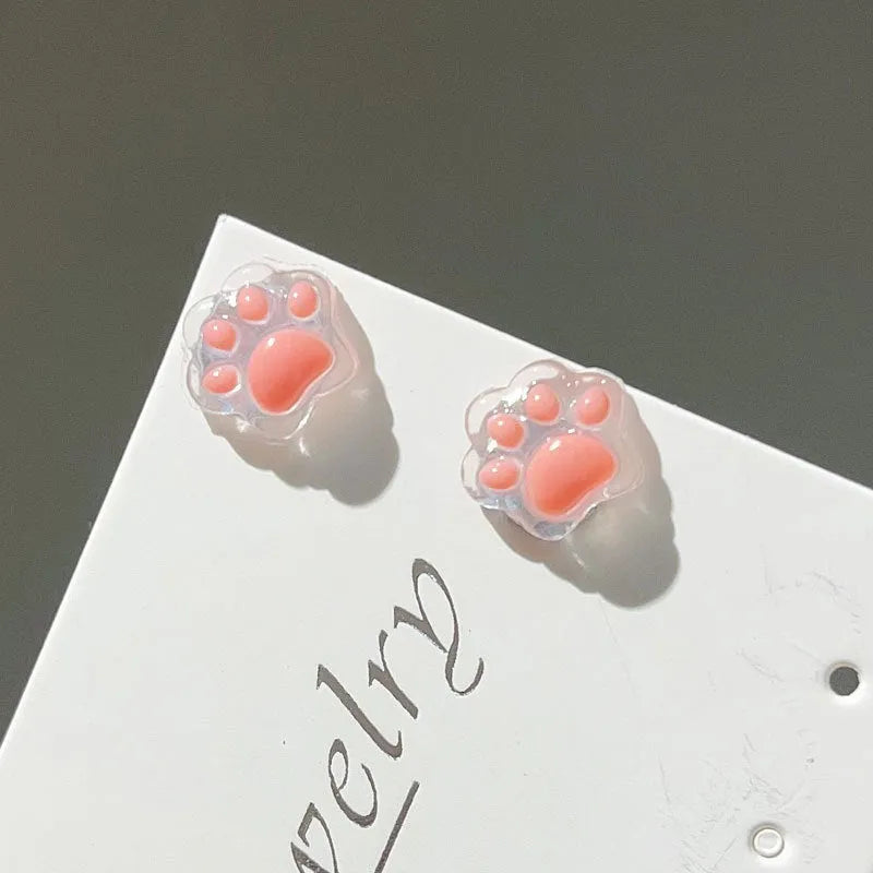 Cat paw magnetic ear clips in transparent pink colour with plastic resin finish, packaged as one pair