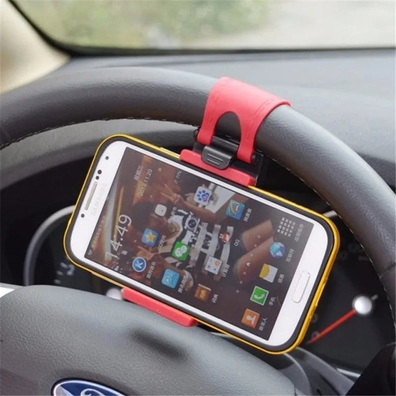 Black universal steering wheel phone holder clip mounted on a car steering wheel, holding a smartphone.