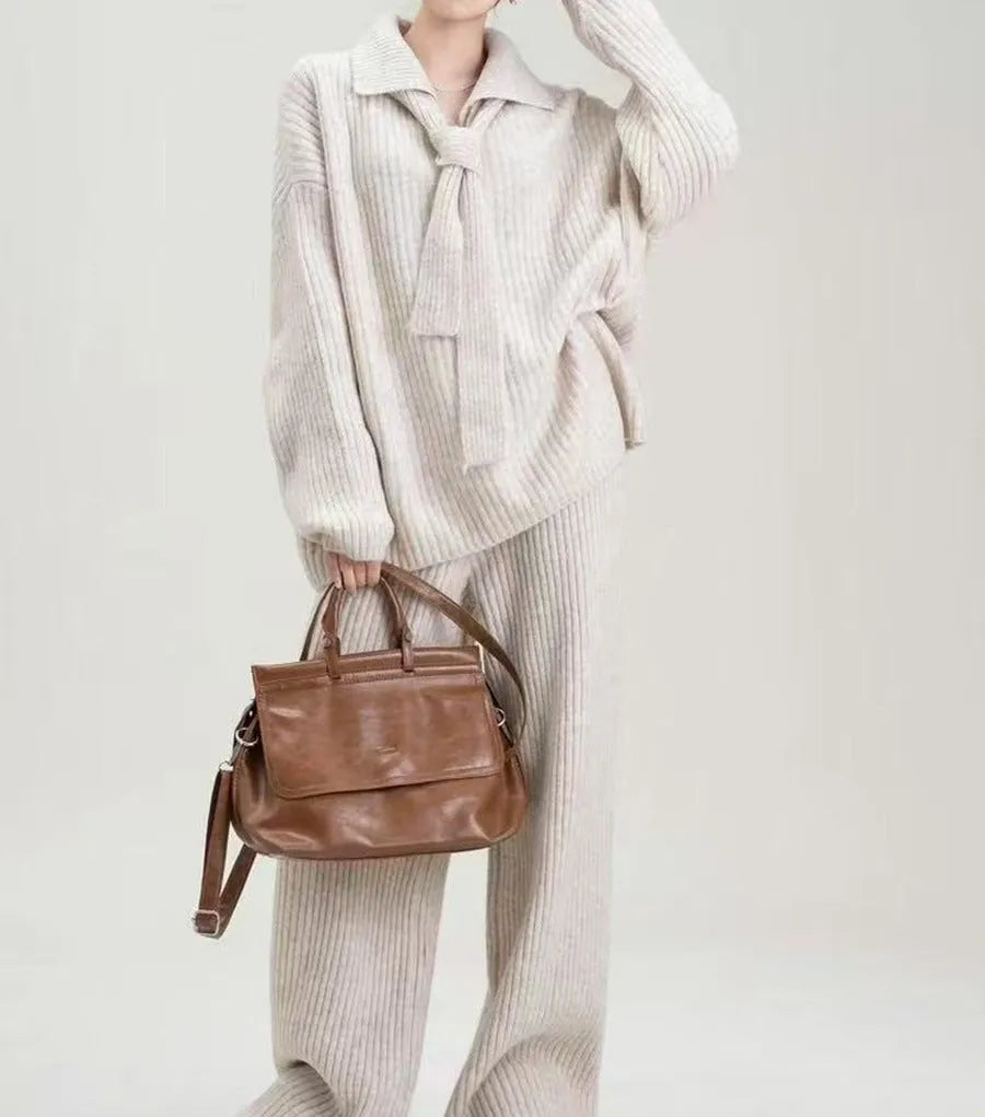 Beige women's knitted sweater suit set with collage stitch detail on top and trousers on a hanger.