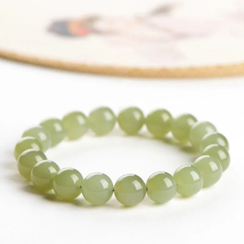 A polished Hetian jade bead bracelet in deep clear water colour on a wrist.