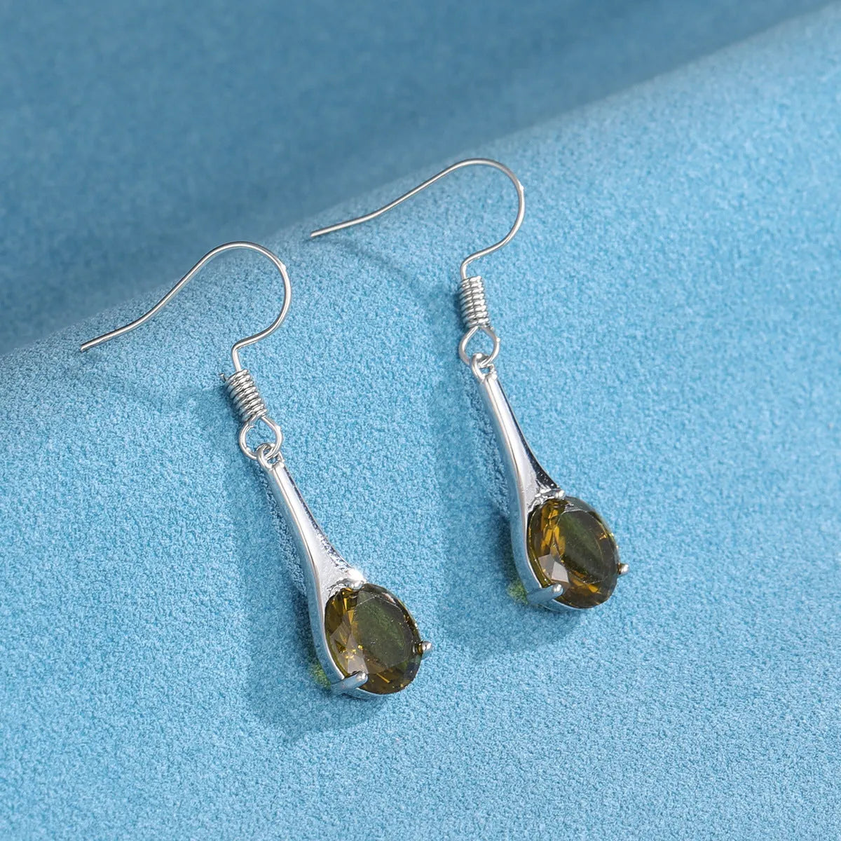 Olive green topaz coloured drop earrings with a water drop shape and retro style on a white background.