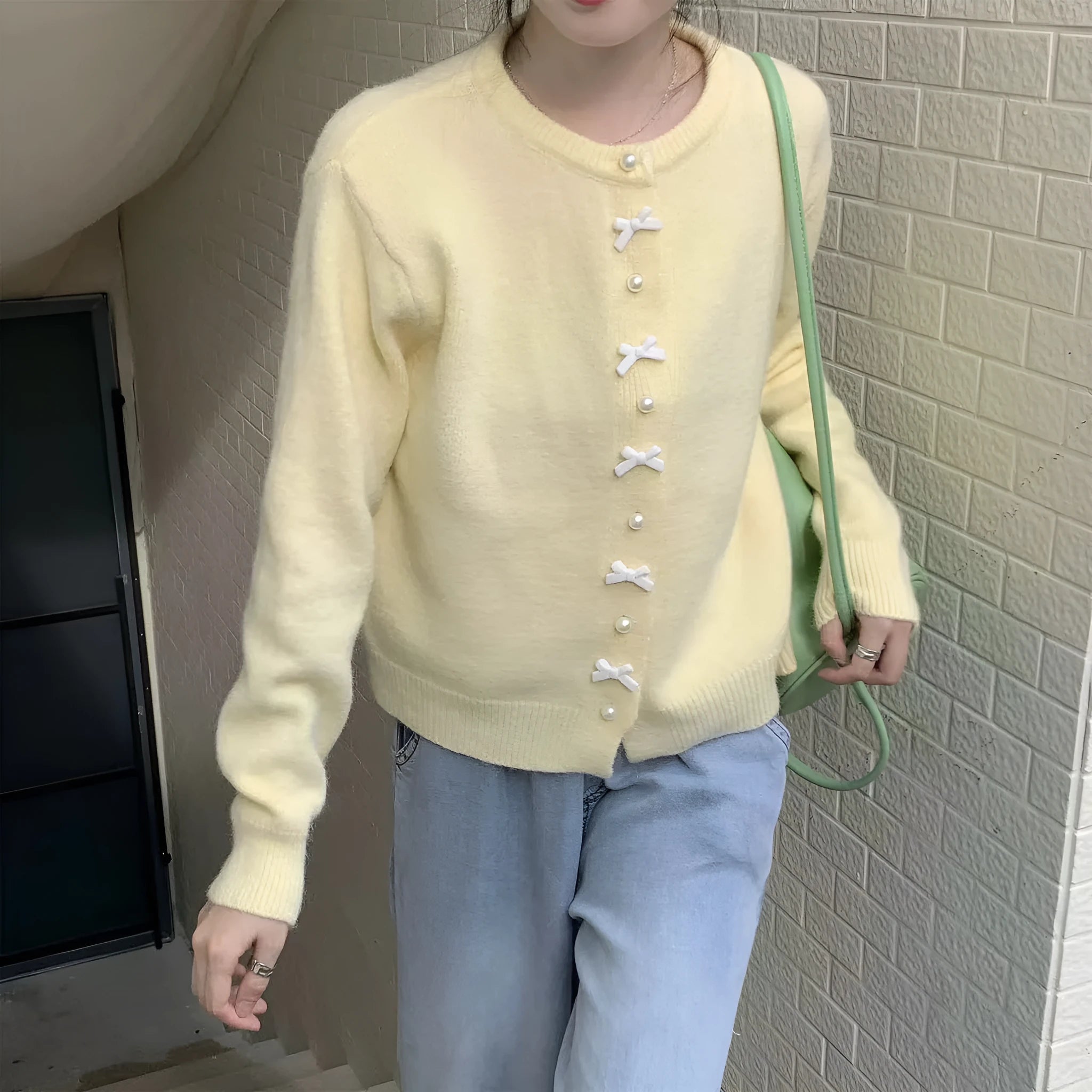Women's cardigan sweater with a bow and pearl buttons in a solid colour.
