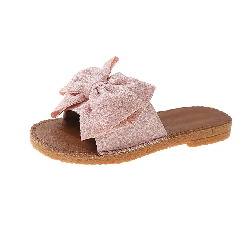 Women's beige suede slip-on sandals with a bow detail and soft rubber sole