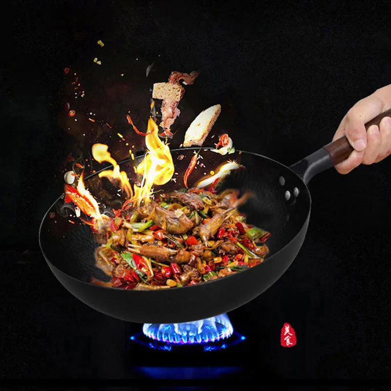 Black traditional cast iron wok with a long wooden handle on a kitchen counter.