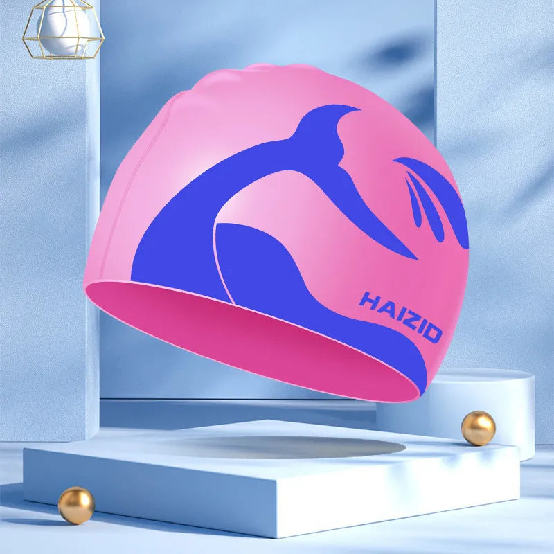 Silicone swimming cap with whale tail pattern and moulded ear protectors in various colours.