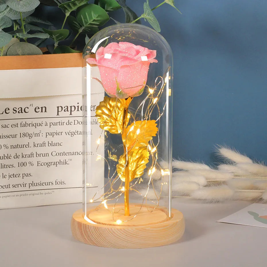 Red eternal rose in glass cover with warm white LED strip lit on dark surface