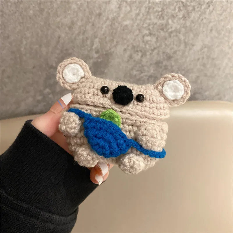 Hand-knitted grey koala bear backpack design earphone cover for Apple AirPods on a table.