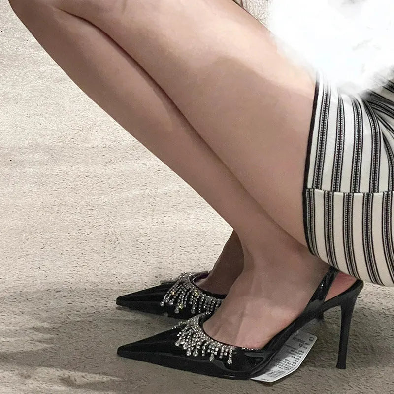 Black women's slingback high heel sandals with rhinestone and tassel decoration on a pointed toe.