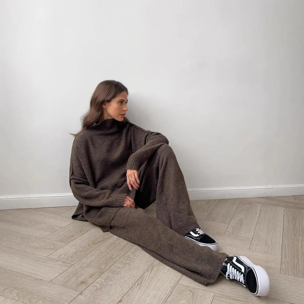 Women's dark grey acrylic knit set with side-slit top and full-length trousers laid flat.