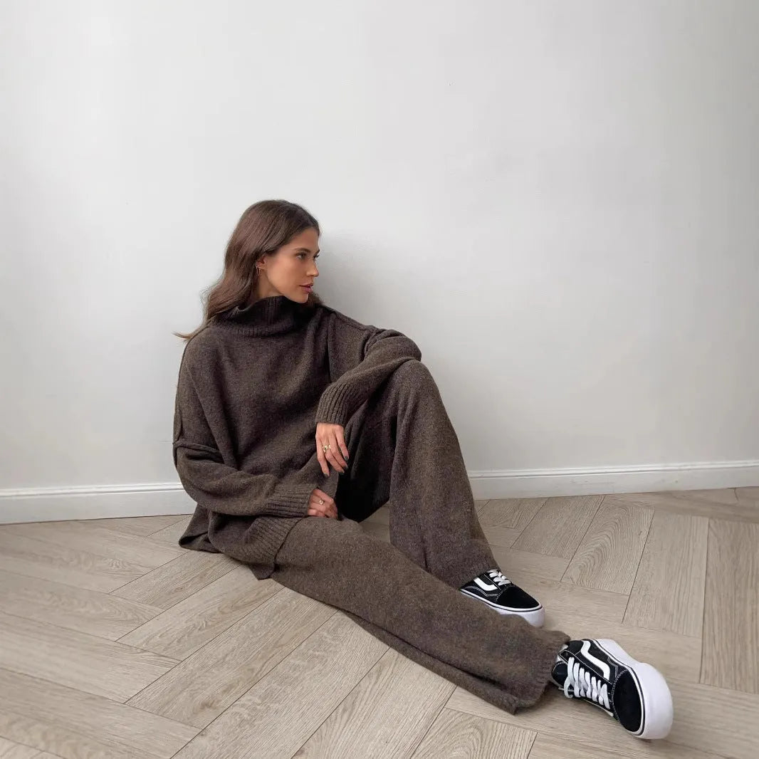 Women's dark grey acrylic knit set with side-slit top and full-length trousers laid flat.