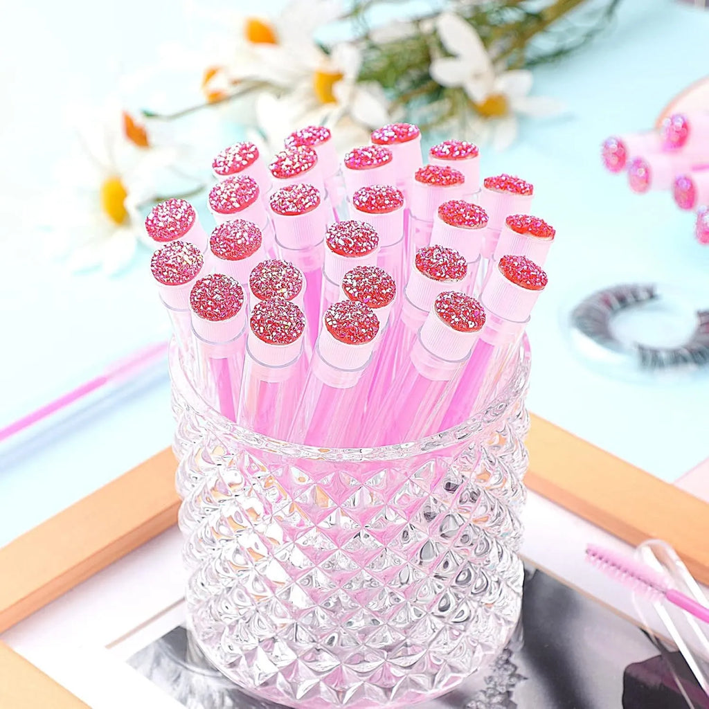 Disposable eyelash mascara brushes in transparent storage tubes showing blue, green, pink and purple colour options