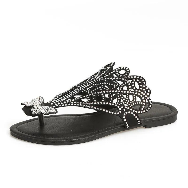 Black women's flat-heeled slip-on sandals with a flip-toe design and rhinestone decoration.