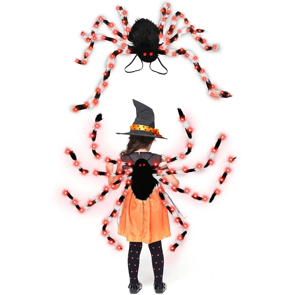Orange plush Halloween spider backpack with purple LED lights lit up, showing the candy bag design.