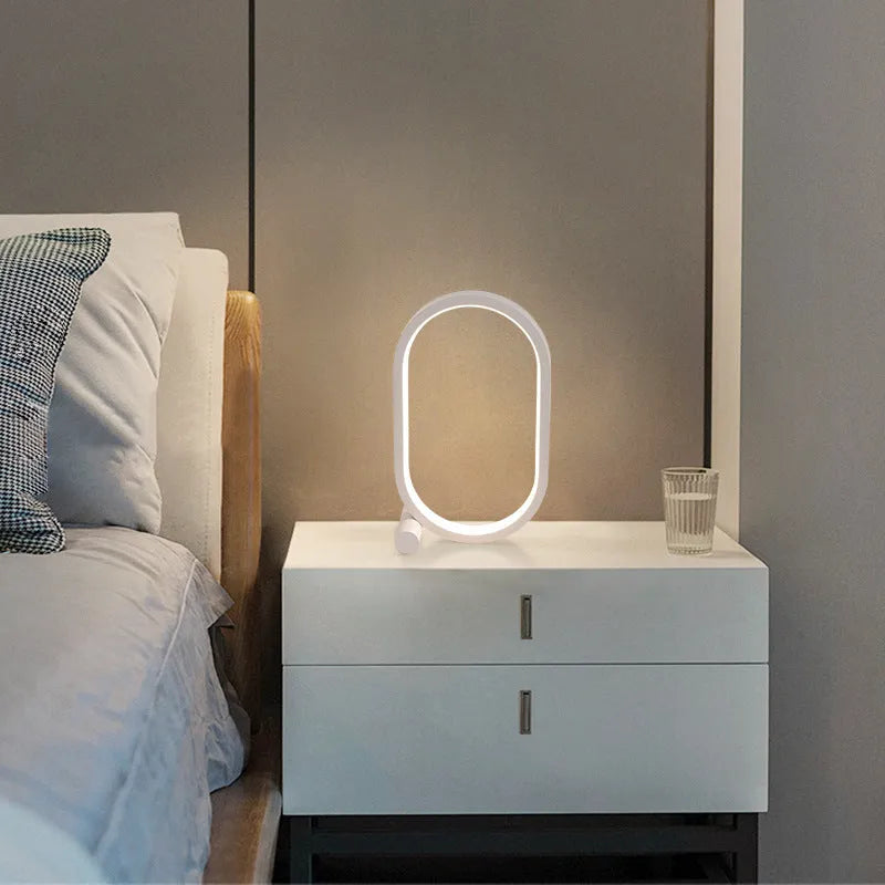 USB plug-in oval acrylic touch control night light with metal base, black finish, on a bedside table