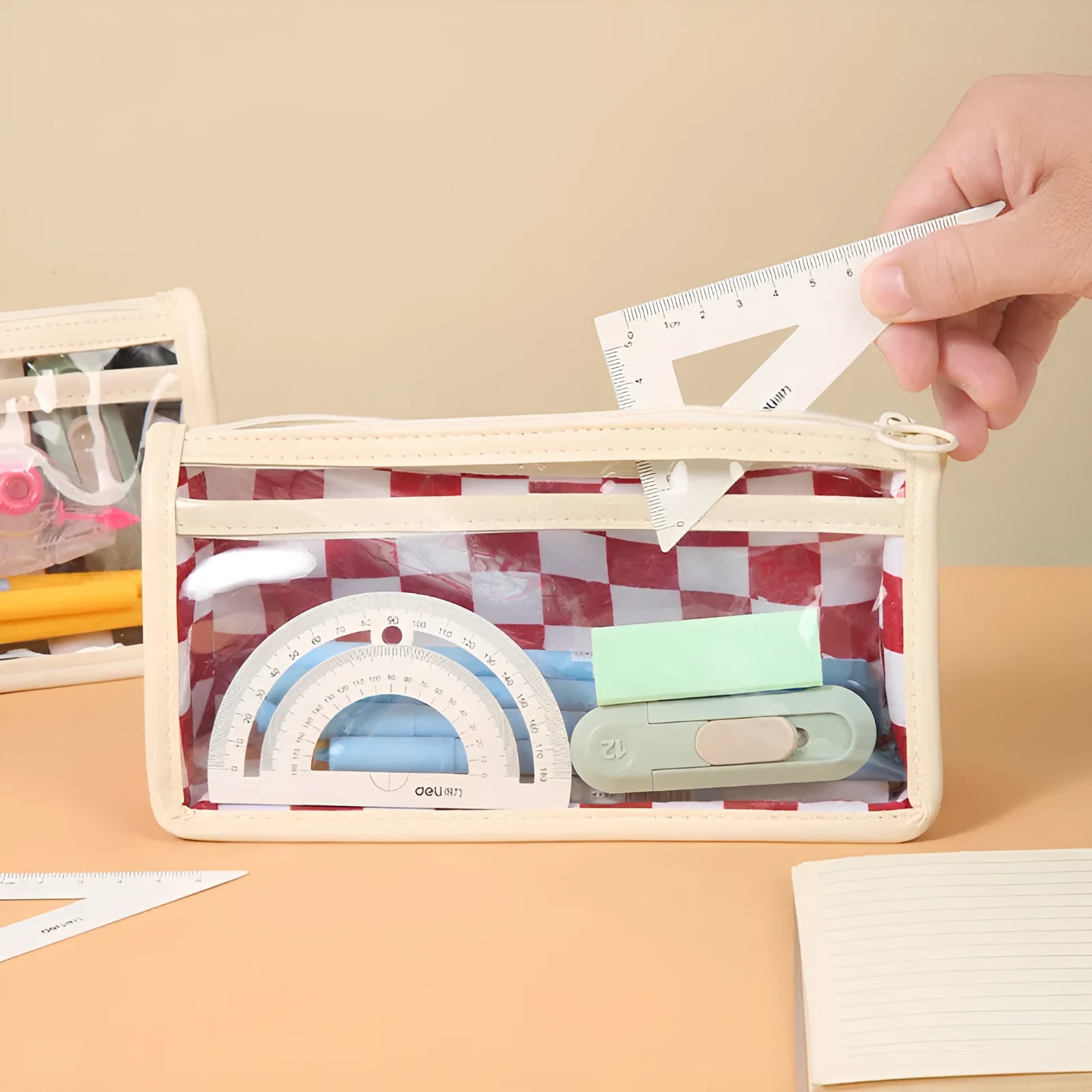 Transparent PVC pencil case with a chessboard pattern, showing pens inside.