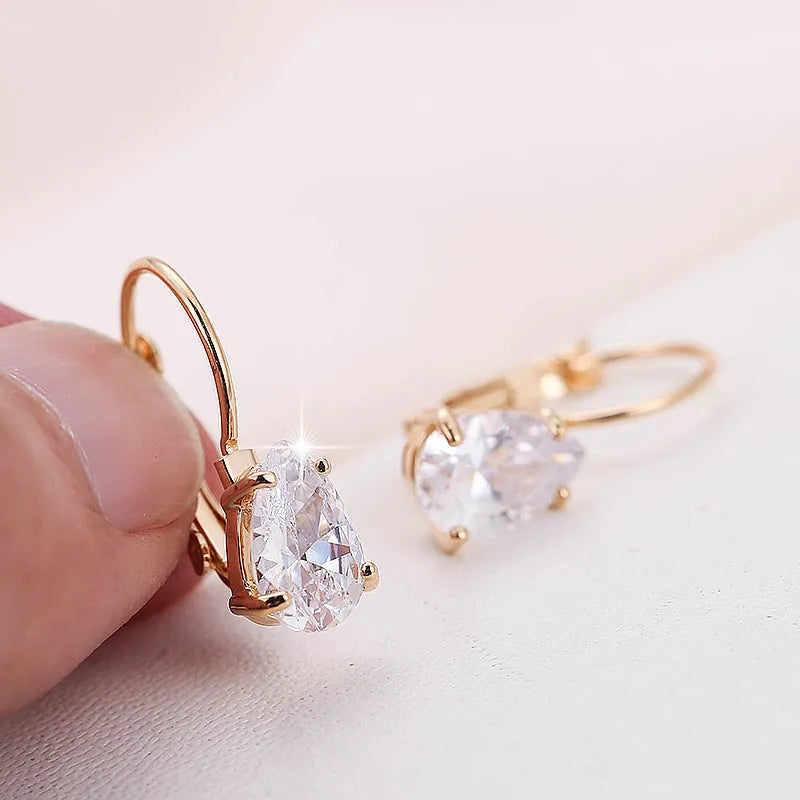 A pair of simple drop-shaped copper earrings with a platinum gem setting, shown in gold colour.