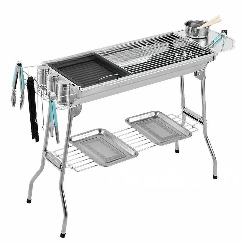 Large stainless steel portable charcoal barbecue oven with iron grill and cooking accessories.