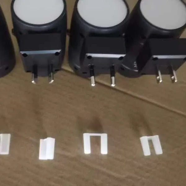 Small white plug-in induction night lamp with a rotatable head on a dark background.