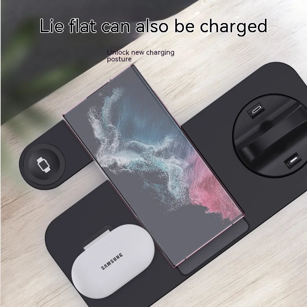 White three-in-one wireless charging station for mobile phone, headphones and smartwatch on a desk.