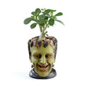 Green personalized resin flower pot with Frankenstein container design and drainage holes for desktop plant display