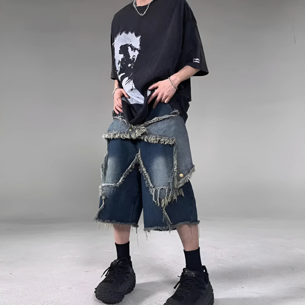 Man wearing blue loose-fit denim shorts with frayed five-pointed star embroidery on the leg.