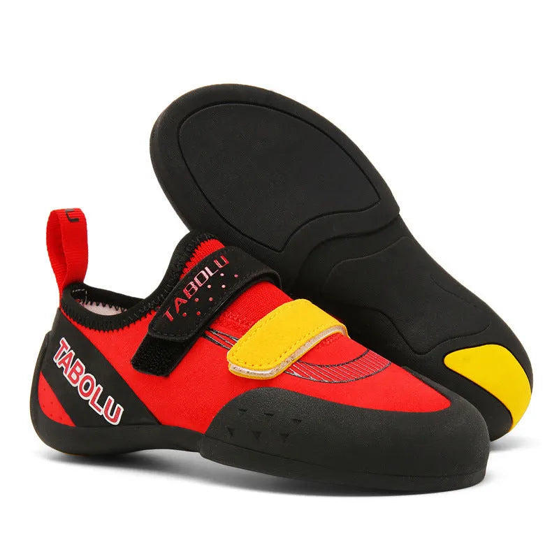 Black and red beginner rock climbing shoes with velcro strap and rubber sole on a climbing hold.