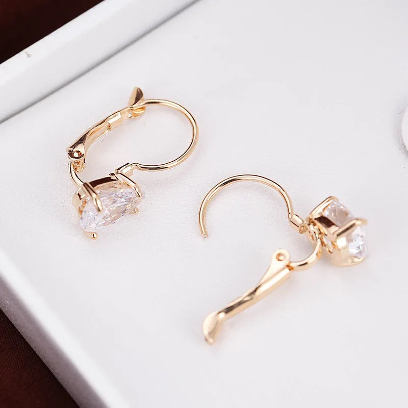 A pair of simple drop-shaped copper earrings with a platinum gem setting, shown in gold colour.