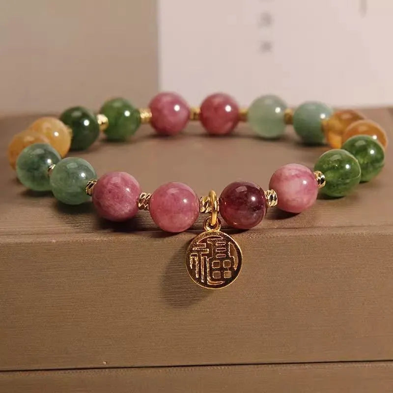 Natural colour tourmaline bracelet with silver electroplated flower and fu character charms on a geometric beaded band.