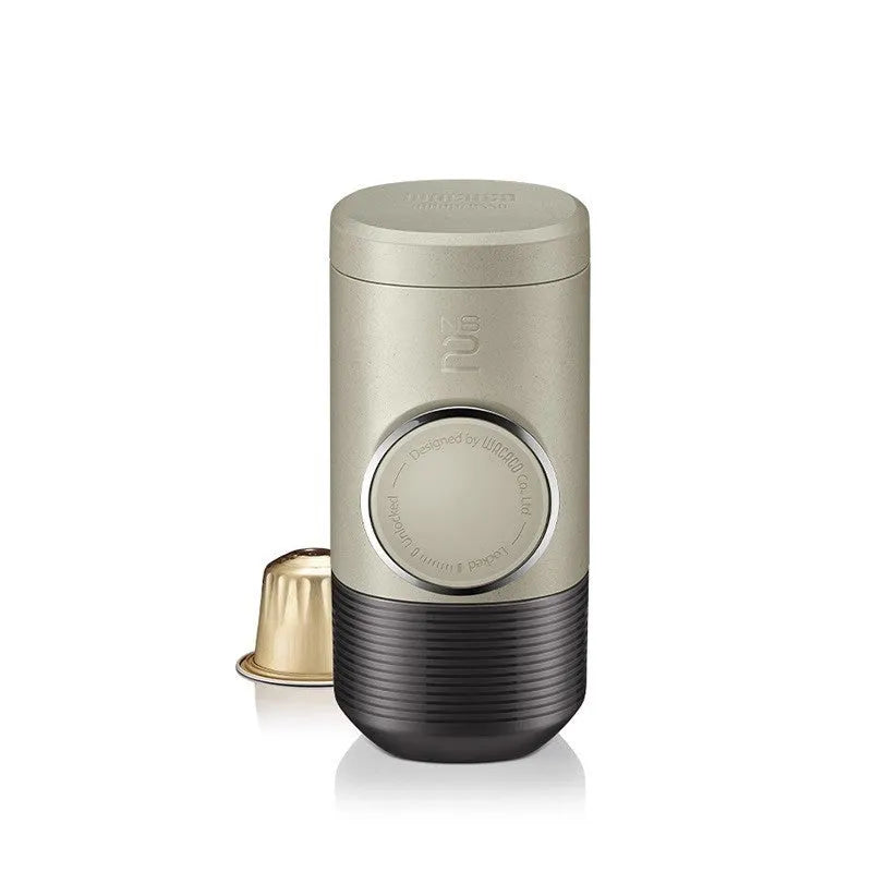 Manual espresso portable capsule coffee machine in olive gray with resin body, 129x70x60mm, on outdoor background