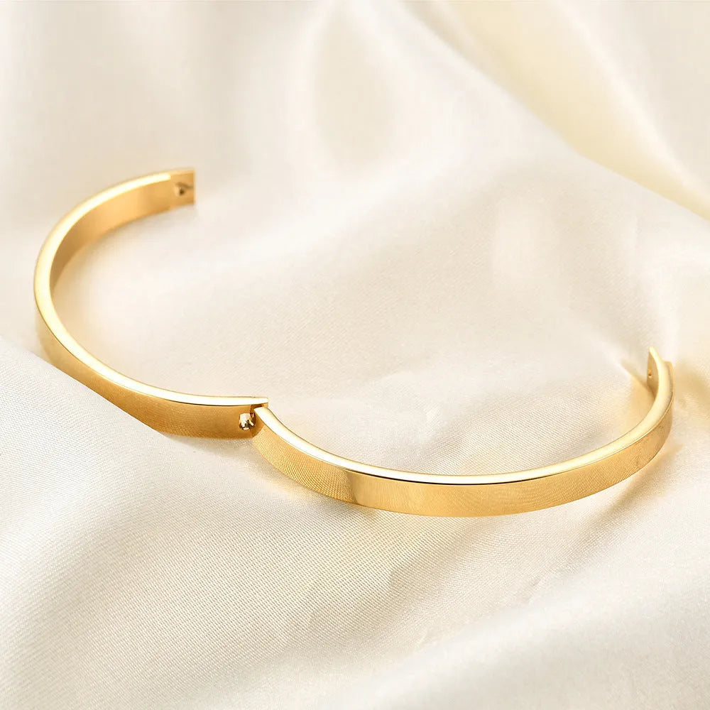 Stainless steel snap bracelet with polished finish in gold colour on a white background