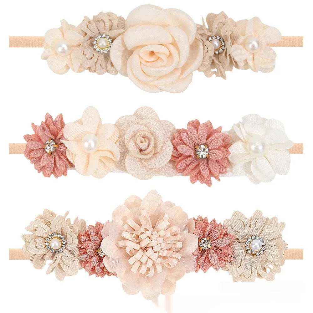Three cloth flower-shaped hair bands for children in different styles on a light background