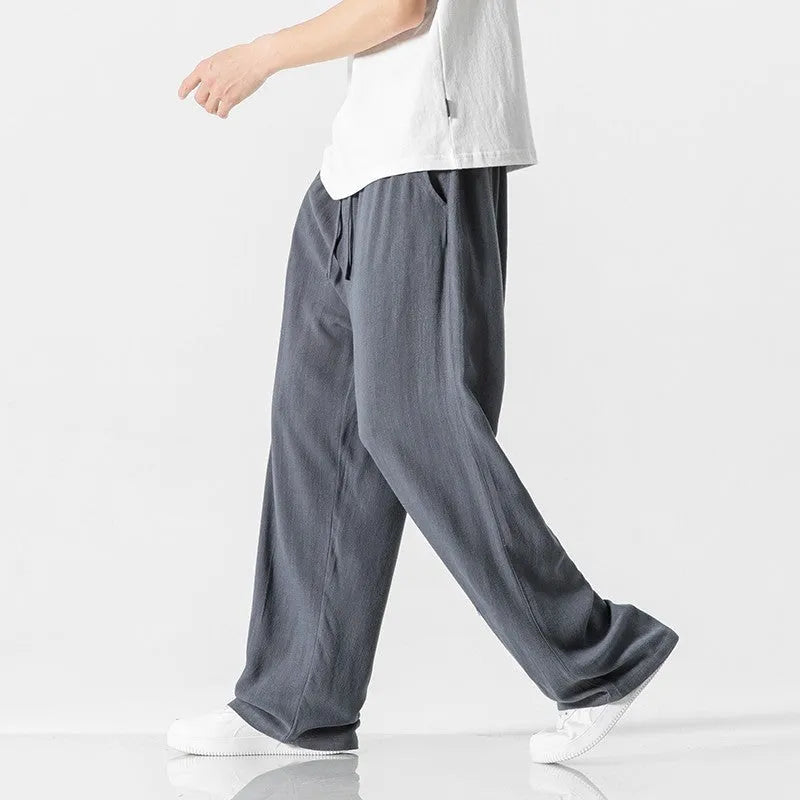 Man wearing beige straight-leg linen bamboo fibre trousers with a drawstring waist and cropped ankle length.