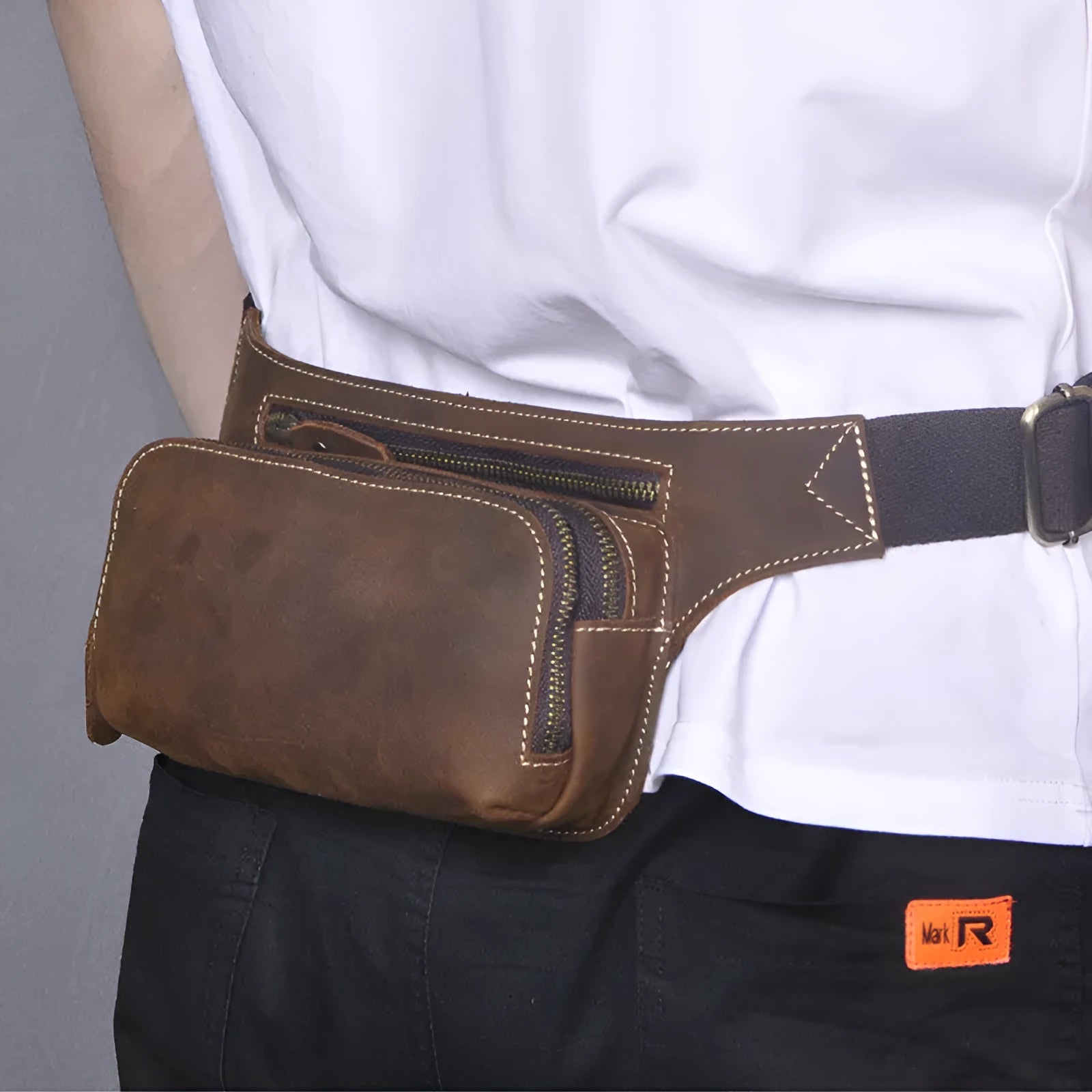 Brown top-grain cowhide men's sports waist bag with pull-cord closure, shown with a 10-inch laptop.