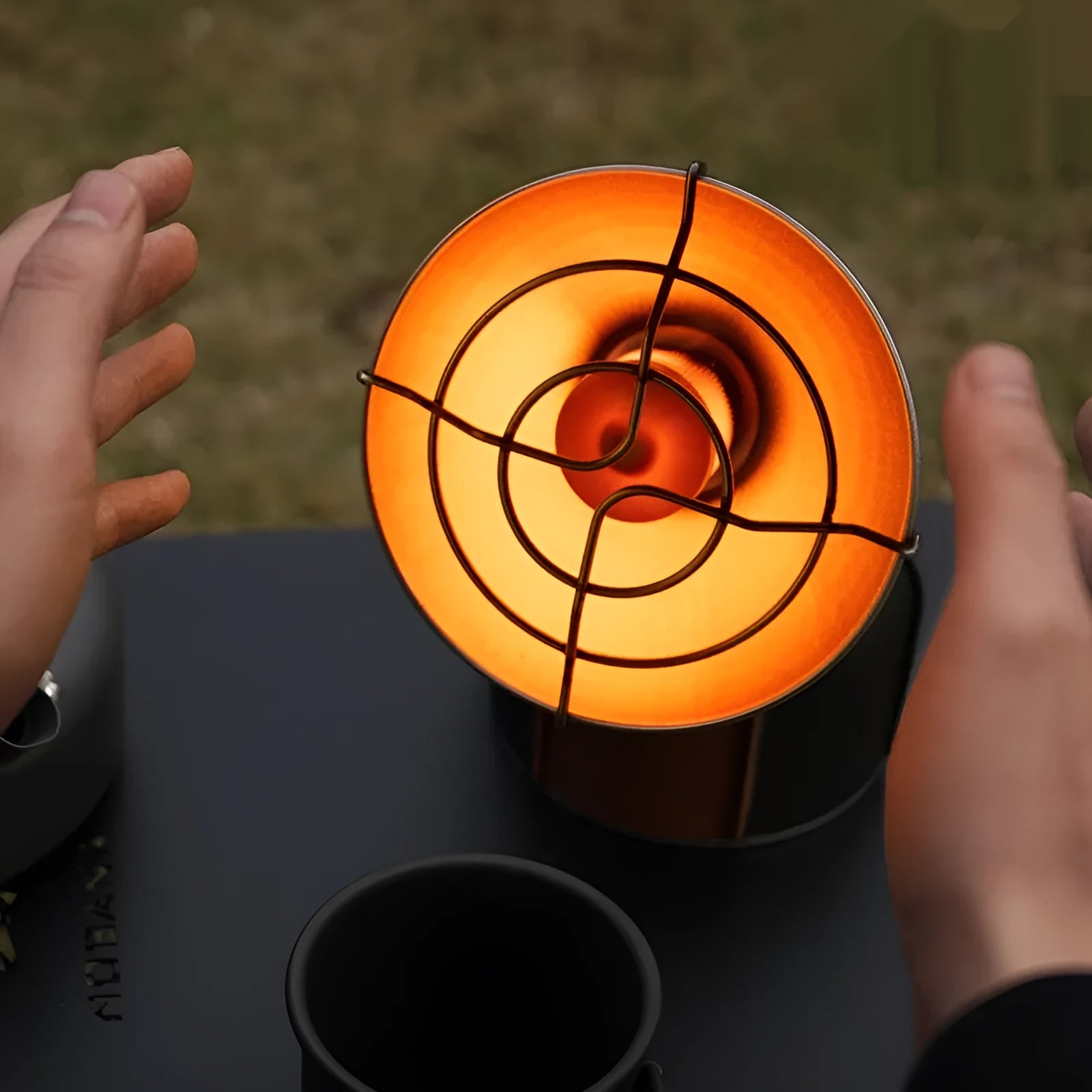 Black and orange portable outdoor heating stove with automatic ignition on a surface.