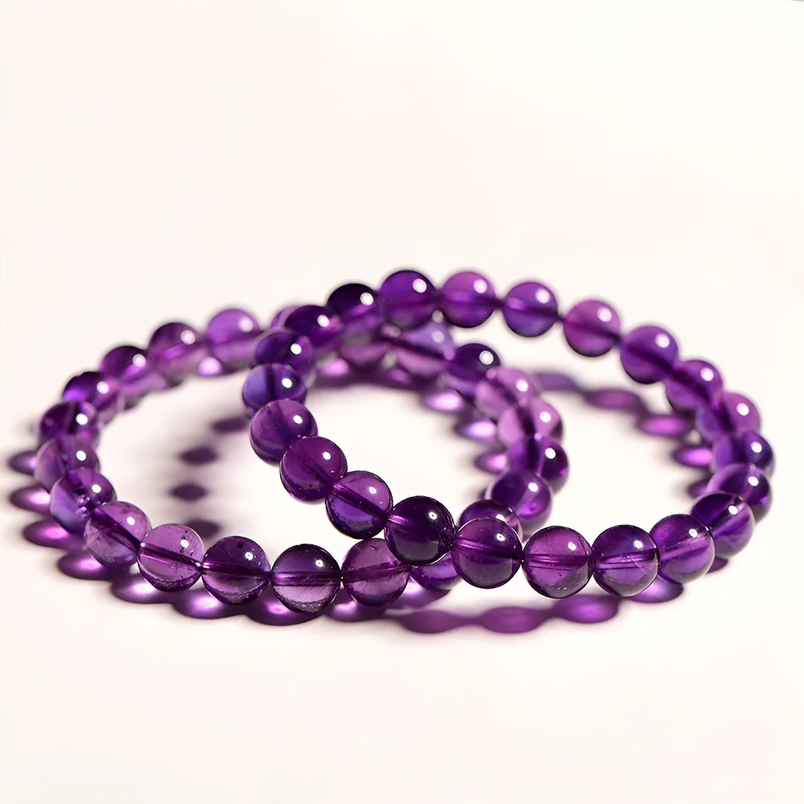 Natural Uruguayan amethyst bead bracelet with scattered polished crystals in deep violet hues on a white background.