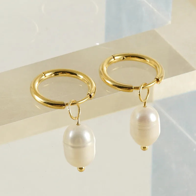 Gold geometric drop earrings with a central freshwater pearl on hypoallergenic posts.