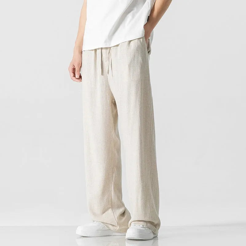 Man wearing beige straight-leg linen bamboo fibre trousers with a drawstring waist and cropped ankle length.