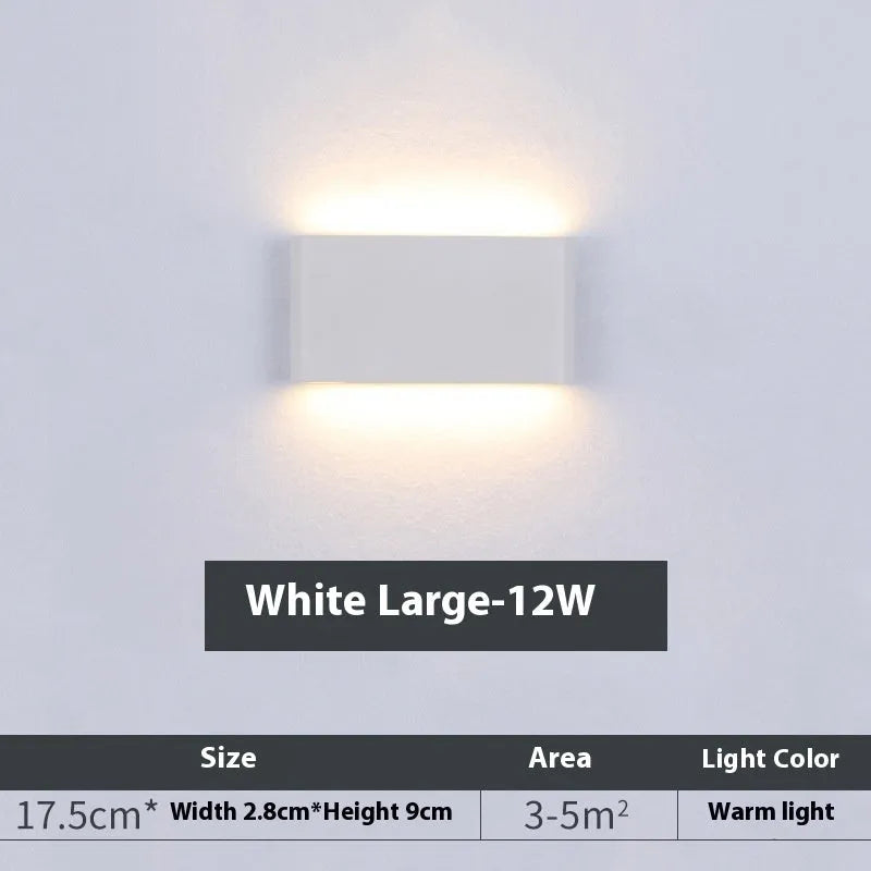 Rectangular LED outdoor wall lamp in black finish with warm light on a brick courtyard wall