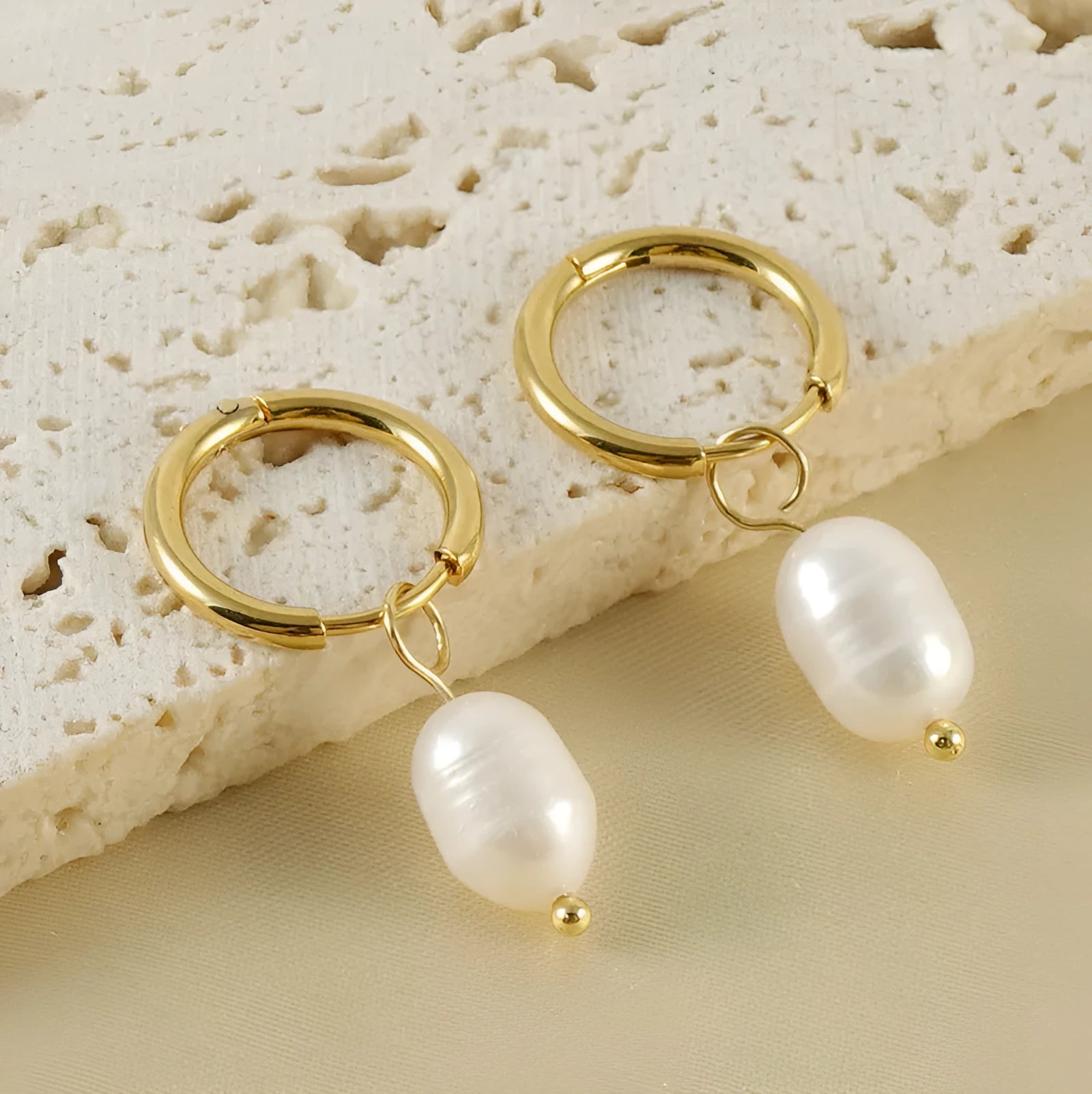 Gold geometric drop earrings with a central freshwater pearl on hypoallergenic posts.