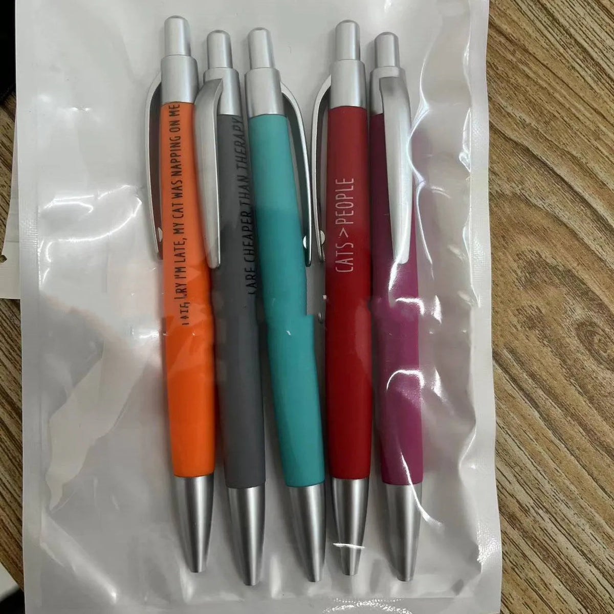 Set of five coloured push-action pens with cat and dog designs in a beaded storage bag