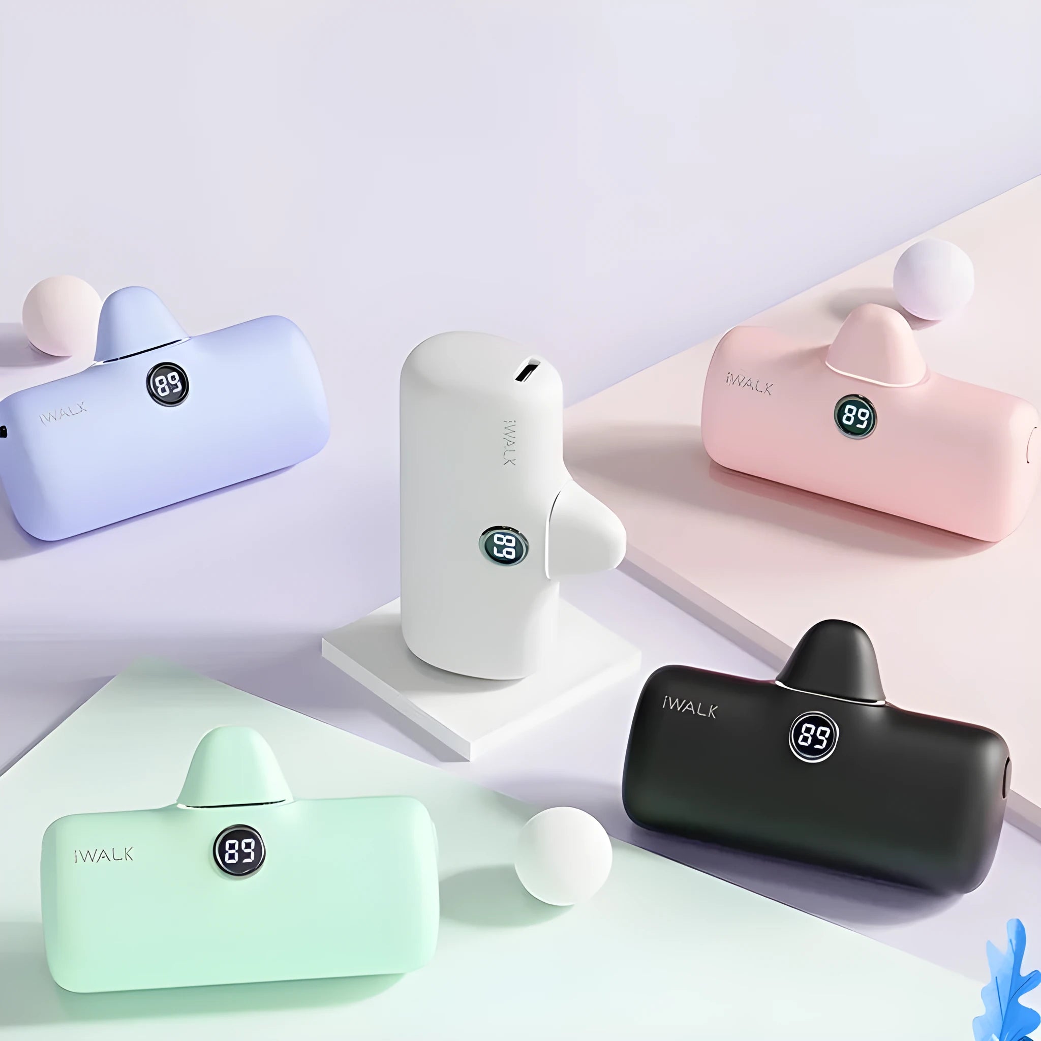 Small white lipstick-shaped power bank showing digital battery percentage display on a wooden table.