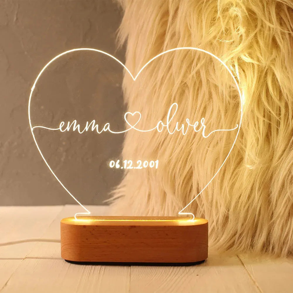 Custom transparent acrylic night light with engraved names and date, lit by an LED base on a table.