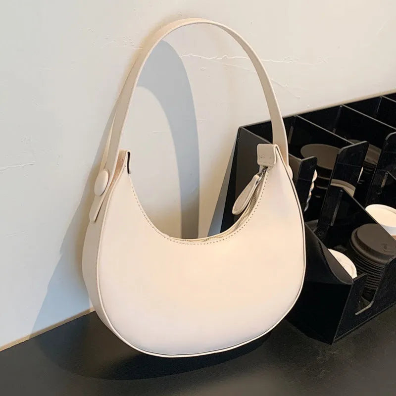 Retro-style dumpling-shaped PU leather shoulder bag in cream yellow showing front sandwich pocket.