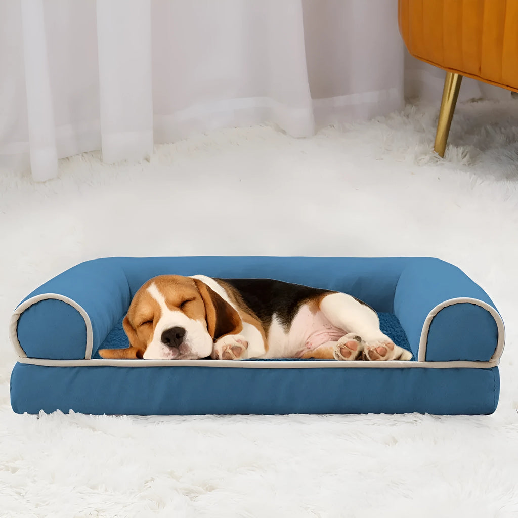 A square grey dog bed with a raised sponge can border on a wooden floor.
