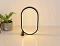 USB plug-in oval acrylic touch control night light with metal base, black finish, on a bedside table