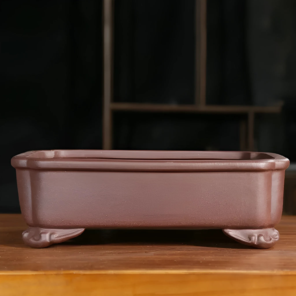 Antique rectangular purple sand bonsai pot with manger design on a floor.