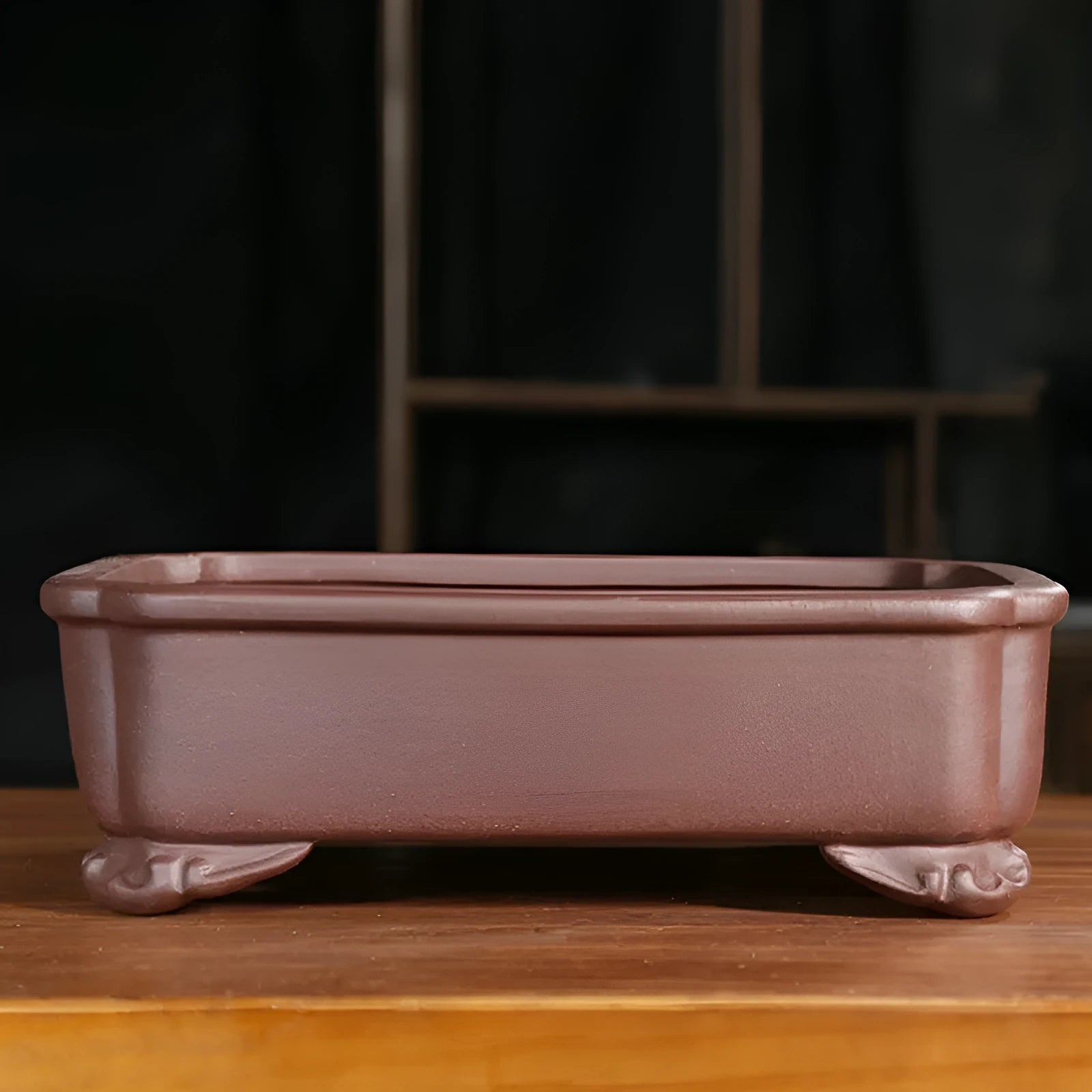 Antique rectangular purple sand bonsai pot with manger design on a floor.