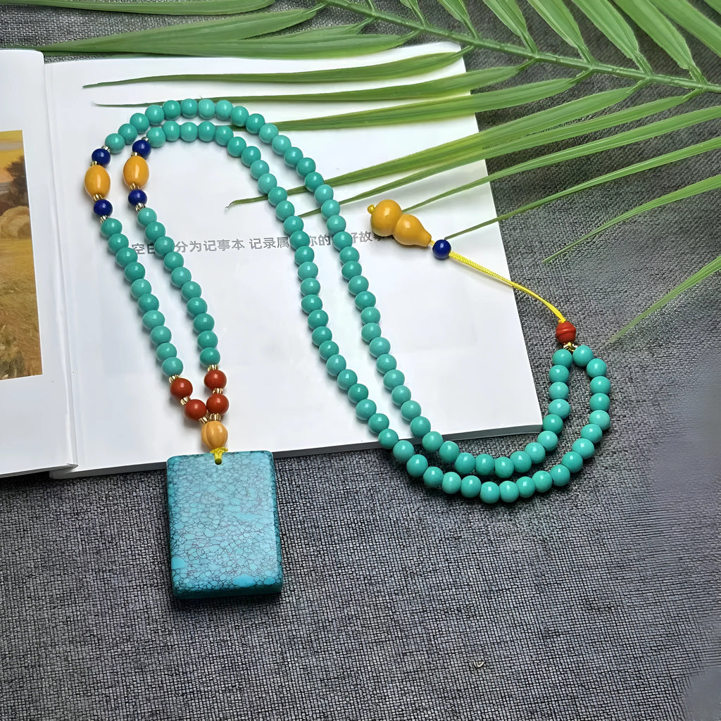 Turquoise stone lucky pendant necklace with detailed hand-woven mesh flower design on an adjustable ball bead chain.