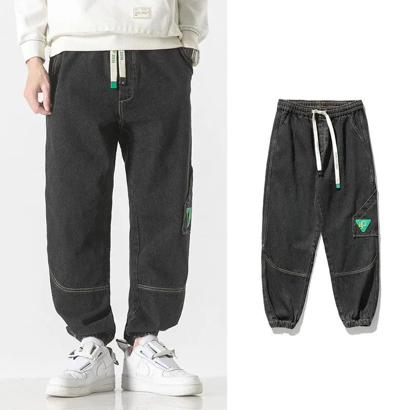 Men's loose-fit cotton tapered trousers in grey shown flat.